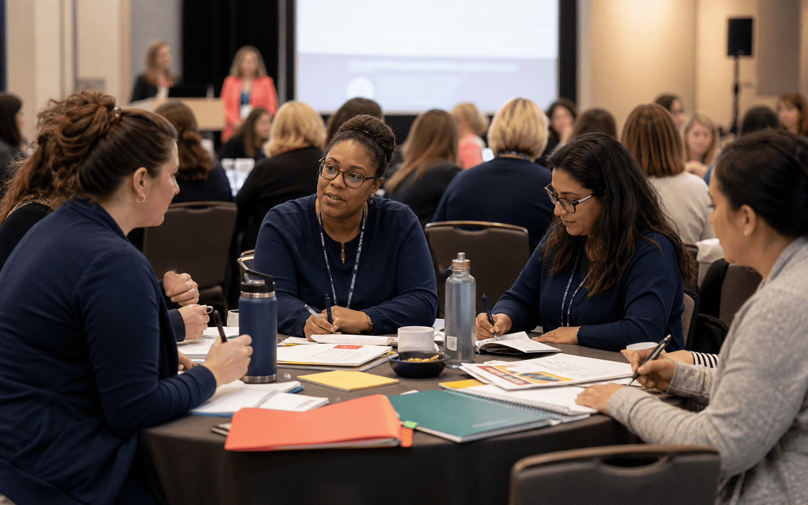 Conference attendees discussing school PBIS materials during a workshop break.